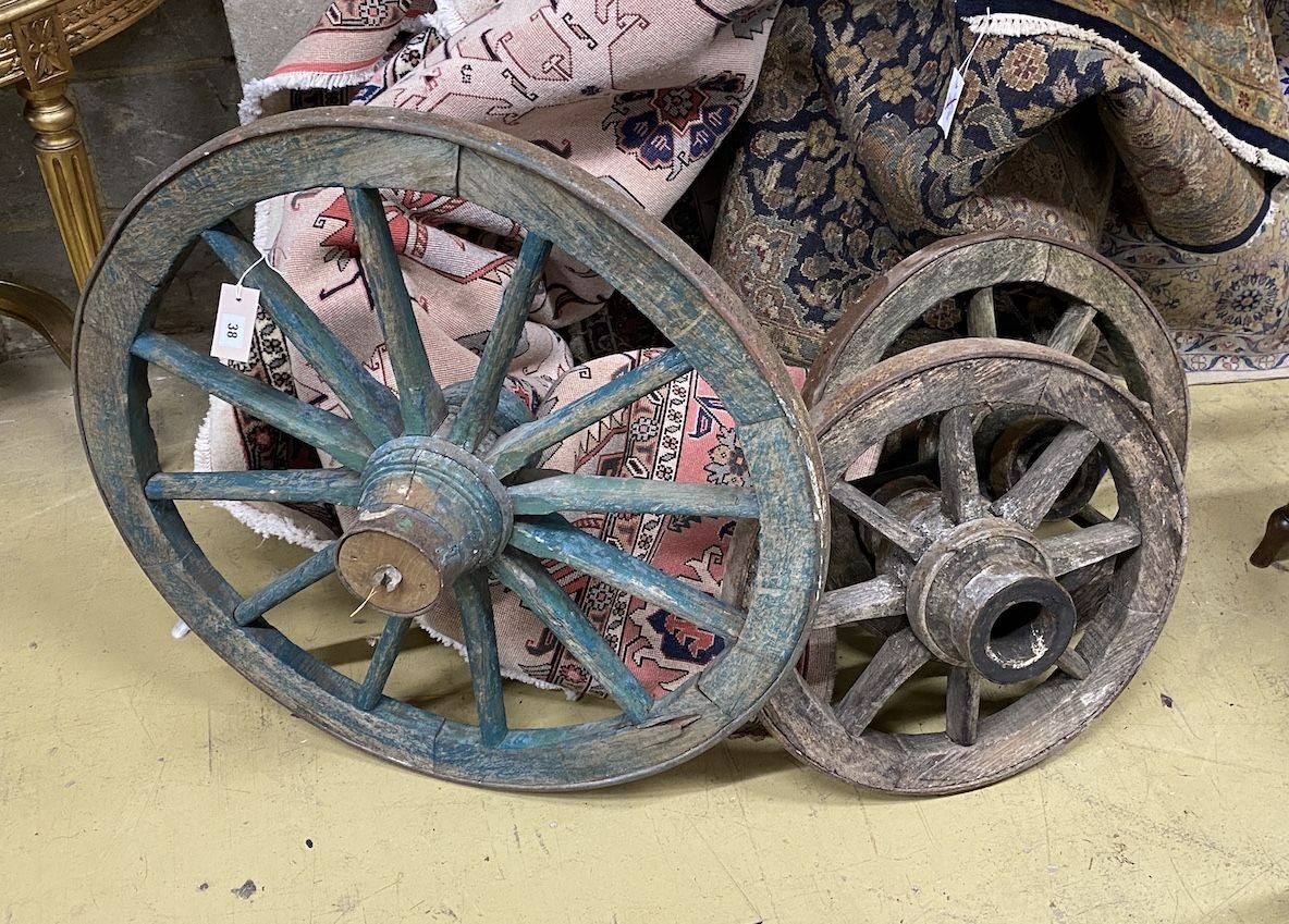 Three vintage spoked cartwheels, a pair and one larger, largest diameter 84cm